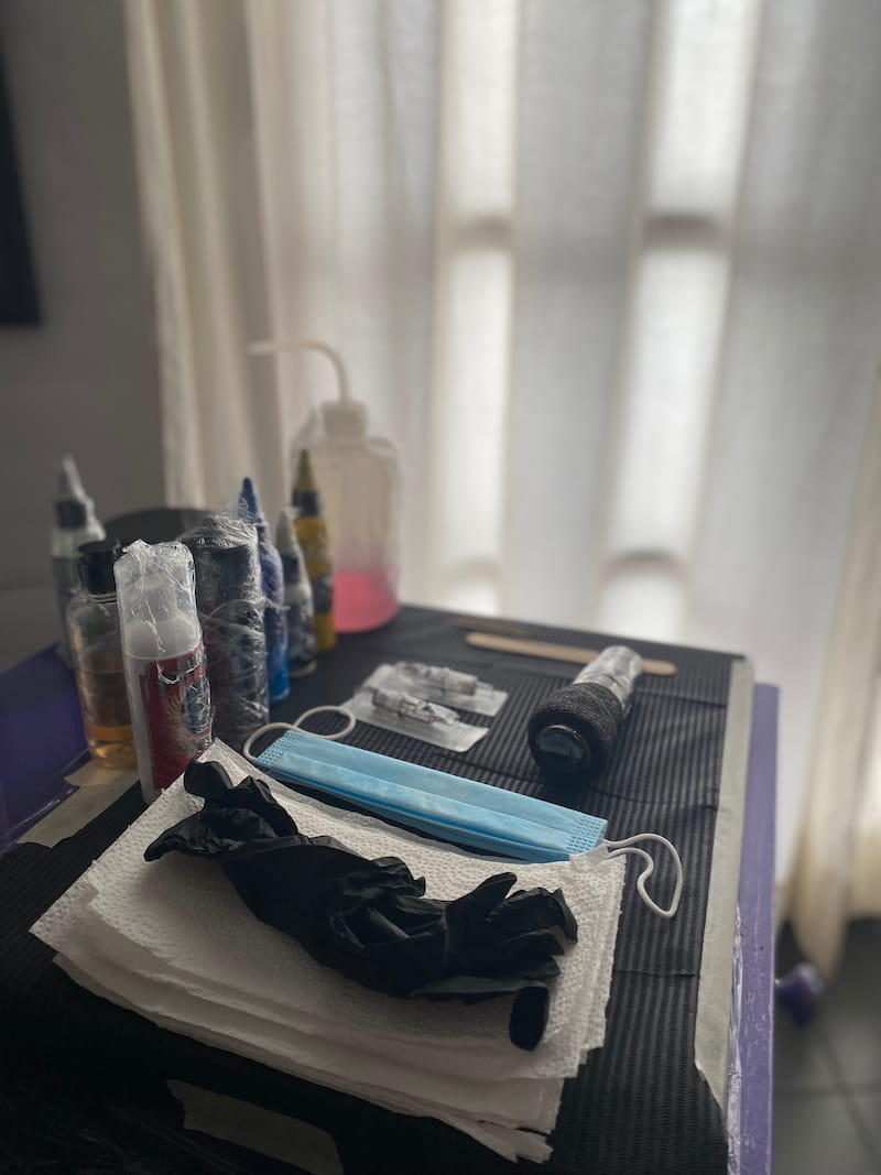 Mesa de trabajo de tatuajes completamente preparada con implementos de seguridad y todo cubierto en papel protector