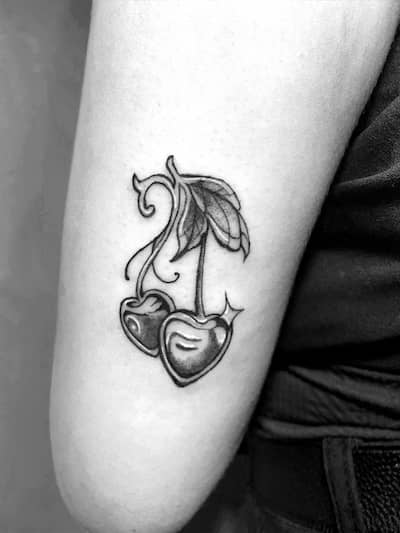 Tatuaje de cerezas con detalles en tinta blanca