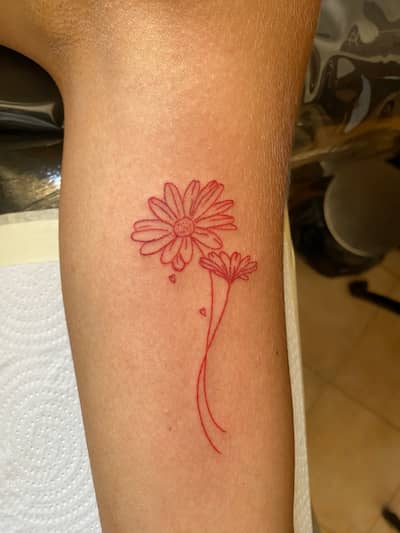 Tatuaje de margarita en línea fina con detalles en rojo